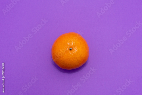 top down bright orange mandarin on purple background