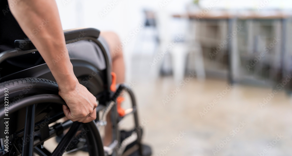 Obraz premium A close-up shot of a person's hand pushing the wheel of a wheelchair, conveying a sense of mobility, independence, and determination. The blurred background suggests movement and an outdoor setting.