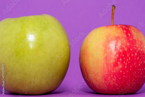 red and green apples on a plain purple background