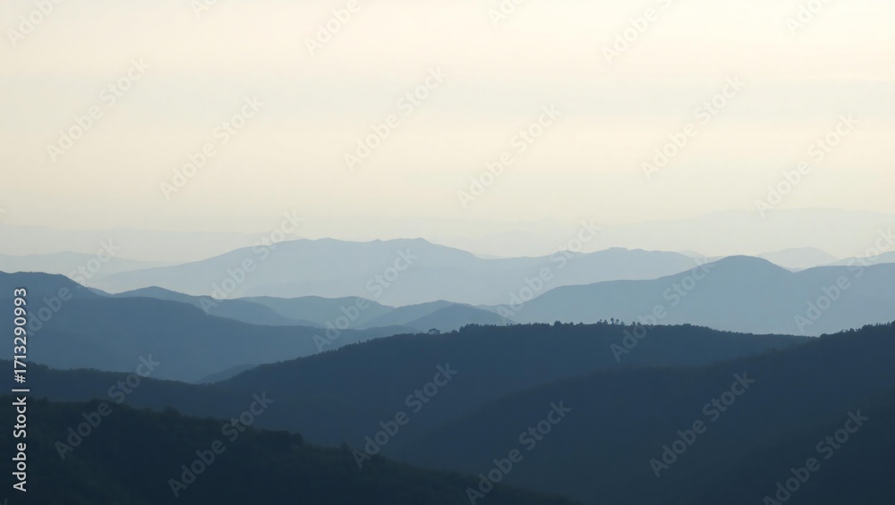 Obraz premium Serene mountain landscape with layers of misty blue peaks under a pale sky