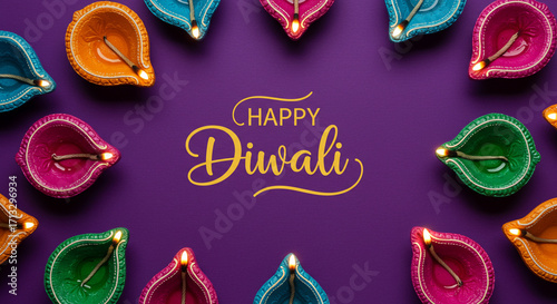 Colorful diwali lamps arranged around happy diwali text on a purple background top down view