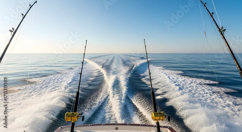View from the stern of a fishing boat speeding across the calm blue ocean, creating a wake in the water.