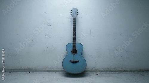 Light-blue acoustic guitar leans against a textured off-white wall