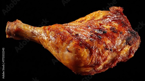 Fototapeta Naklejka Na Ścianę i Meble -  Roasted chicken leg with crispy, browned skin against a stark black background