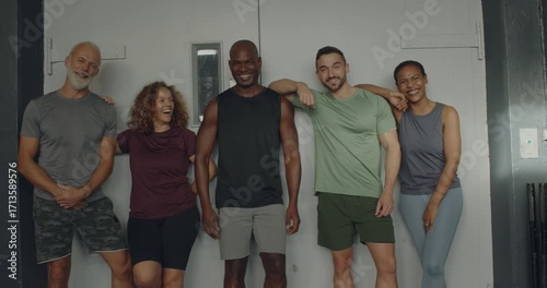 Diverse group of fit people in
sportswear laughing while standing
side by side together after a class in
a gym