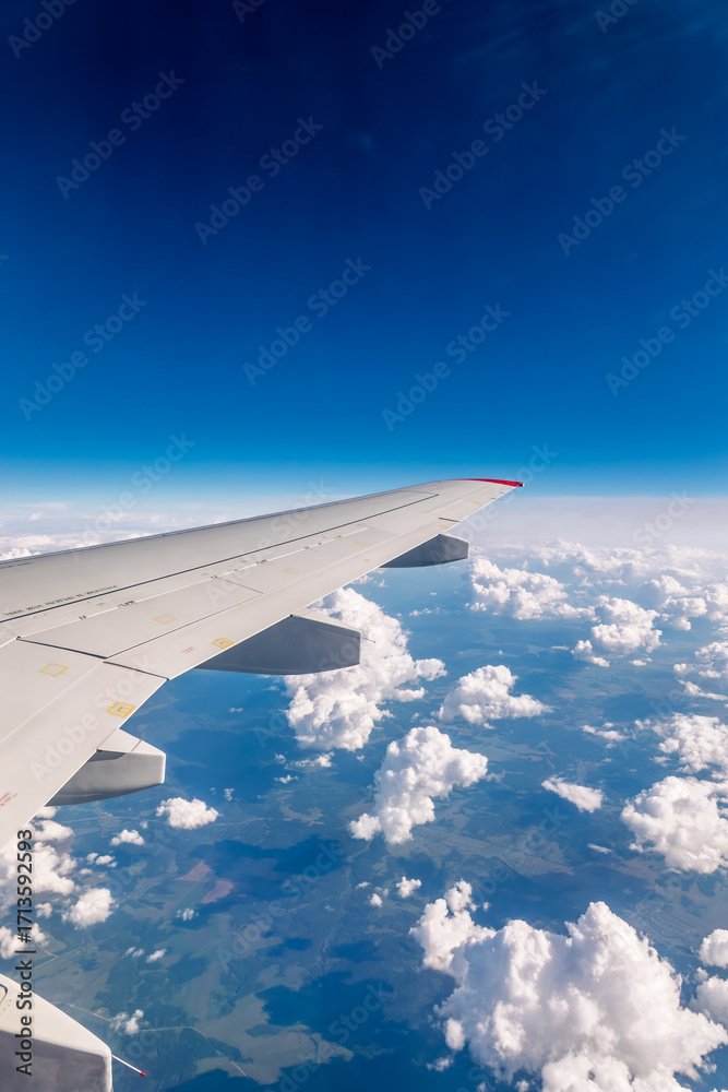 Obraz premium View from the airplane window at a beautiful cloudy sky and the airplane wing
