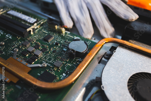 Close-up image of an all-in-one computer interior showing the motherboard, heat pipe cooling system, RAM slot, processor, and electronic components. Inside View of All-in-One Computer Motherboard