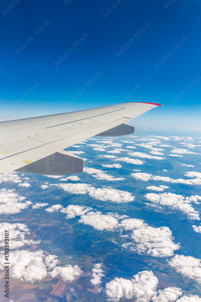 Fototapeta premium View from the airplane window at a beautiful cloudy sky and the airplane wing