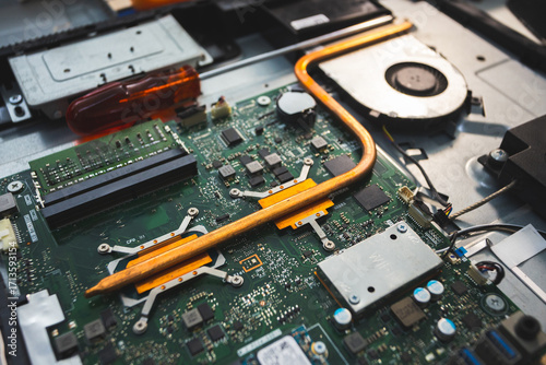 Close-up image of an all-in-one computer interior showing the motherboard, heat pipe cooling system, RAM slot, processor, and electronic components. Inside View of All-in-One Computer Motherboard
