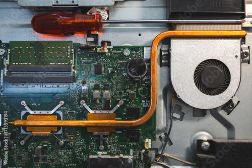 Close-up image of an all-in-one computer interior showing the motherboard, heat pipe cooling system, RAM slot, processor, and electronic components. Inside View of All-in-One Computer Motherboard