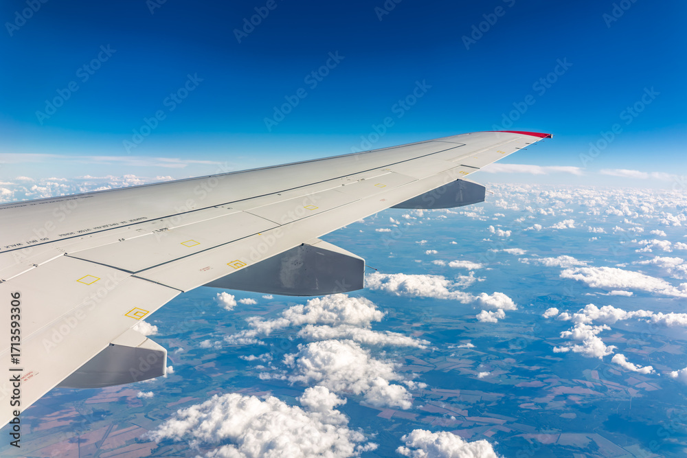 Fototapeta premium View from the airplane window at a beautiful cloudy sky and the airplane wing