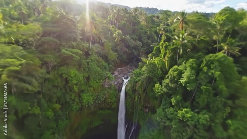 Cascading waterfall plunges into a dark pool surrounded by dense, lush, green jungle