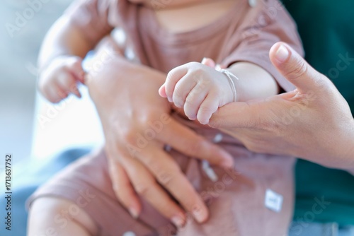 A baby's hand tightly grasps its mother's finger, a mother's love and care for her child.