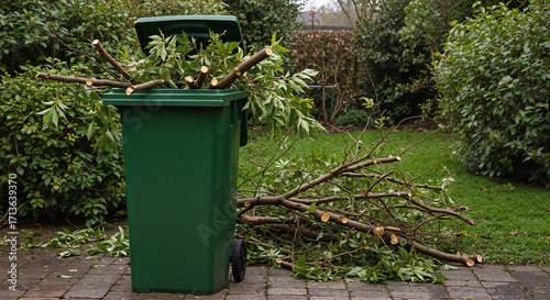 Green trash bin overflowing with branches and garden waste outdoors  