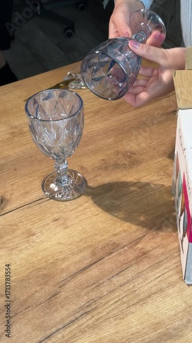 A set of glass goblets. A woman unboxing and reviewing stemmed glass goblets. Vertical video.