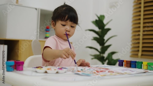 happy toddler girl painting watercolor in paper at home