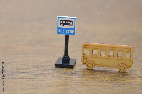 a toy bus and a bus stop sign effectively represents the routine of public transit, waiting, and city travel in a minimalist style.