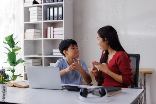 Asian teacher and student communicating using sign language in classroom