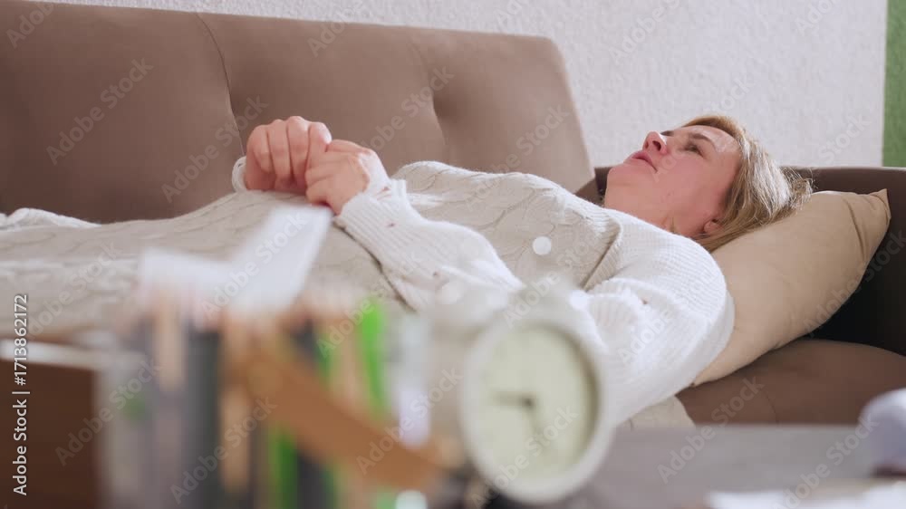 Inner explorer lying faced up on sofa with pillow support under head conversing softly in contemplative room with blurred pencils and retro clock on nearby desk creating serene therapeutic ambiance