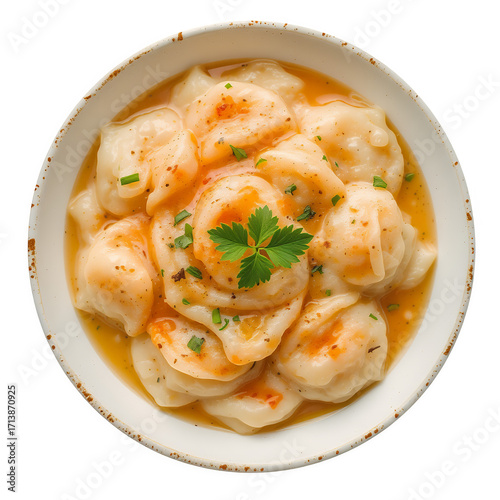 A bowl of savory dumplings in a rich orangey broth garnished with fresh parsley and chives