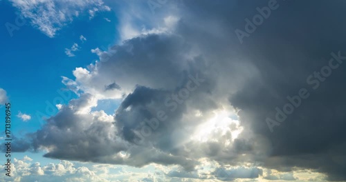 A dramatic timelapse of a brewing summer storm. Sunbeams break through dark thunderclouds as the first raindrops begin to fall.