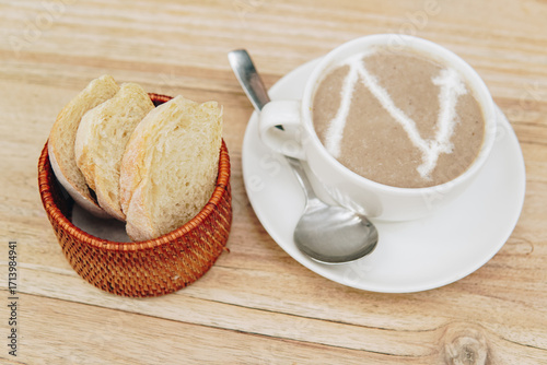 Close up view of a gazpacho soup served with a basket of sourdough on the side.