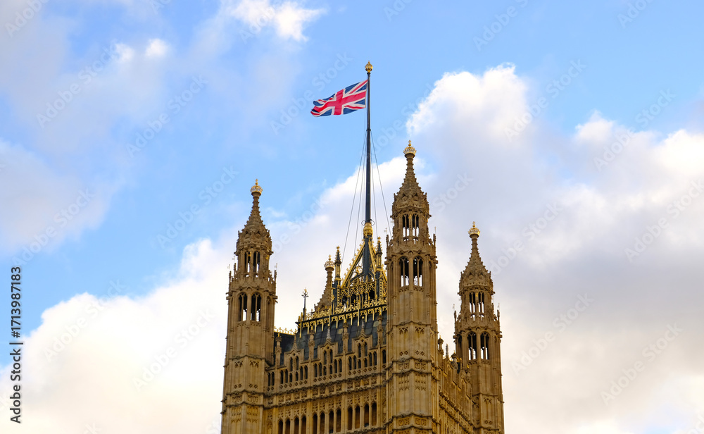 Obraz premium British national flag waving on building of the Palace of Westminster (Houses of Parliament) in London. Flag of Great Britain is one of state symbols of state of Great Britain and Northern Ireland.