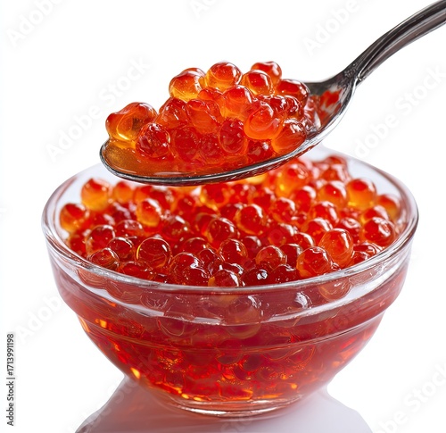 Red caviar in a glass bowl, scooped with a spoon