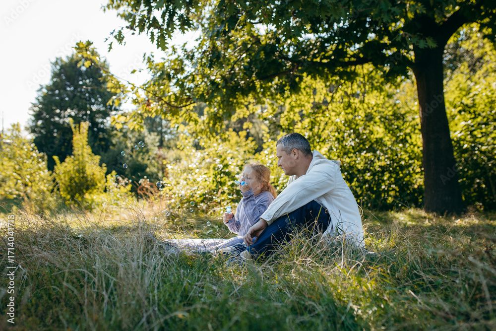 Fototapeta premium Adult father and little daughter are walking in the park