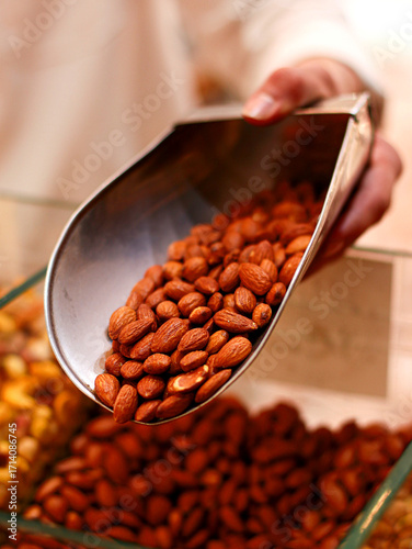 Tableau sur toile Metal scoop filled with roasted almonds being displayed in bulk food section