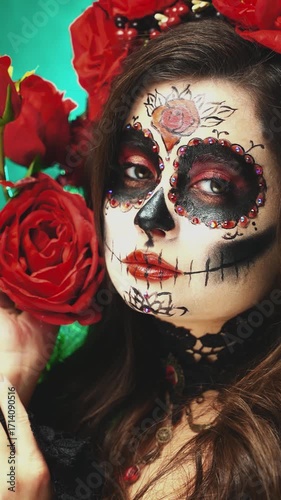 Close-up portrait woman sugar skull make-up on face eyes red lips roses white skin paint dark hair. Halloween makeup holiday body art. Girl Calavera, day of the dead. vertical video crop short reels