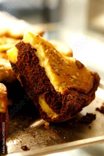 Bilde på lerret Piece of chocolate cake topped with golden nut layer, positioned upright on tray
