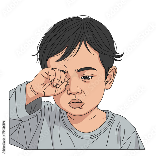 A young child with dark hair rubs their eye with their hand, appearing tired or sleepy.