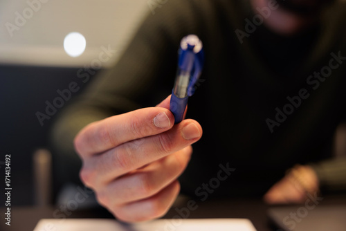 concetto sull'offrire una penna per firmare. mano di giovane adulto caucasico che porge una penna in primo piano