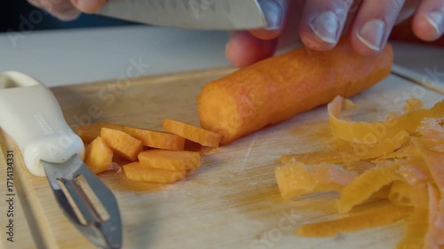 Mans hands chopping carrot on cutting board