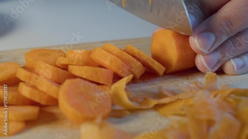 Mans hands chopping carrot on cutting board