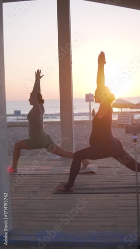 Vertical video of pregnant women practicing yoga at sunrise by the sea. The calm atmosphere, gentle exercise, and natural setting highlight wellness, relaxation