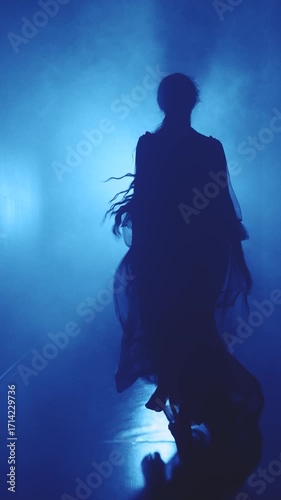 dark silhouette scared woman running away along black corridor hall. Adult girl in long dress back rear view horror creepy night scene lightning blue color light film. vertical video crop short reels