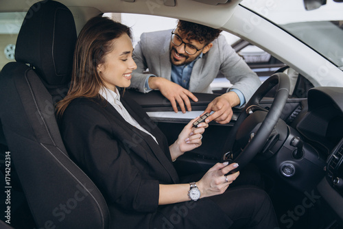 Woman receiving car key from salesman in dealership