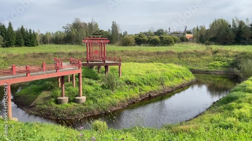 A Serene and Beautiful Landscape Featuring a Red Pavilion Next to a Peaceful Stream