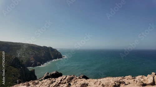 Rocky cliffs drop steeply into the Atlantic Ocean at Cabo da Roca, the westernmost point of Europe. The rugged landscape and endless blue sea create a dramatic and wild coastal atmosphere