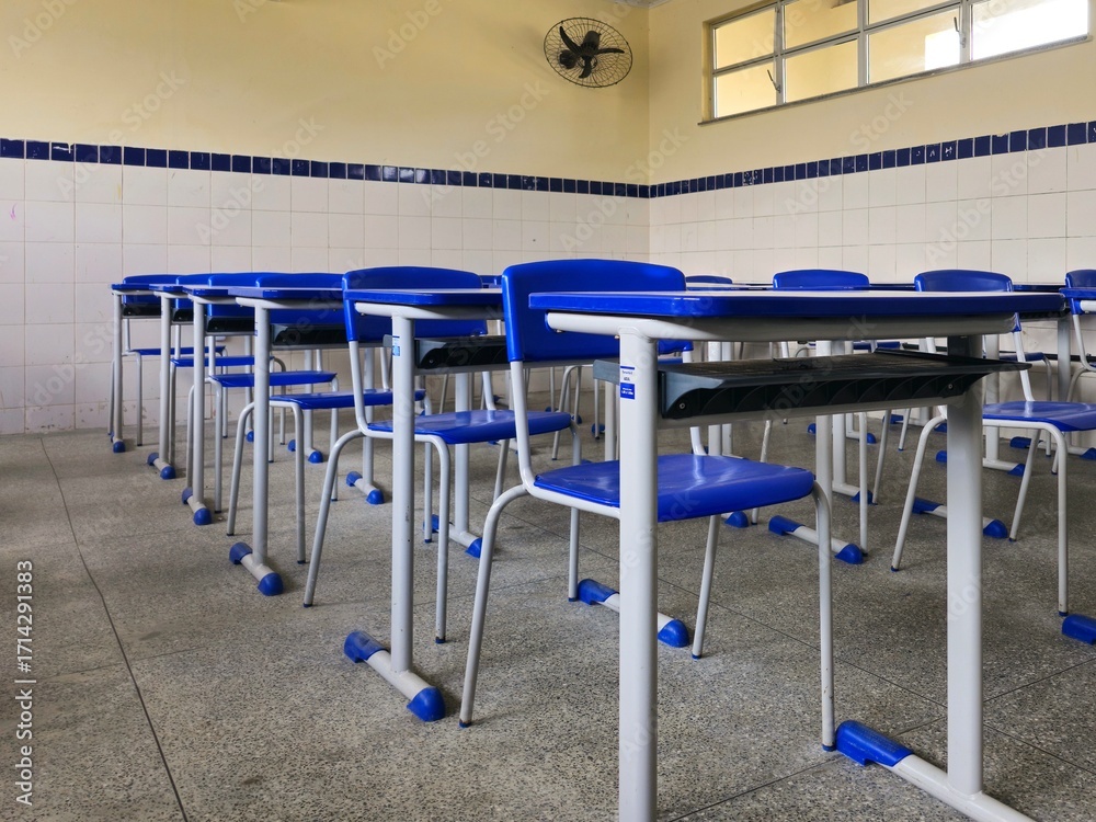 Naklejka premium Cadeiras e mesas de uma sala de aula vazia em uma escola pública.