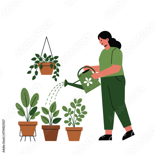 A woman in green clothes waters her collection of indoor potted plants with a watering can.