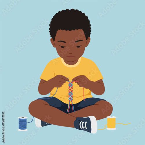 Boy crafting a friendship bracelet, sitting cross-legged on the floor, spools of thread nearby