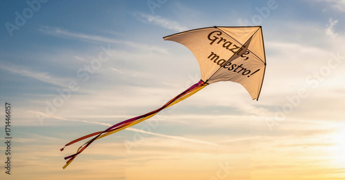 Off-white kite with Italian gratitude message at sunset