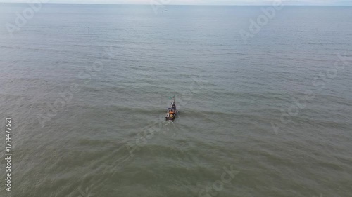 Aerial view of a wooden boat sailing on a murky sea. Drone footage follows the boat.
