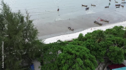 Aerial view of the beach. Drone footage of the receding seashore with wooden boats nearby.