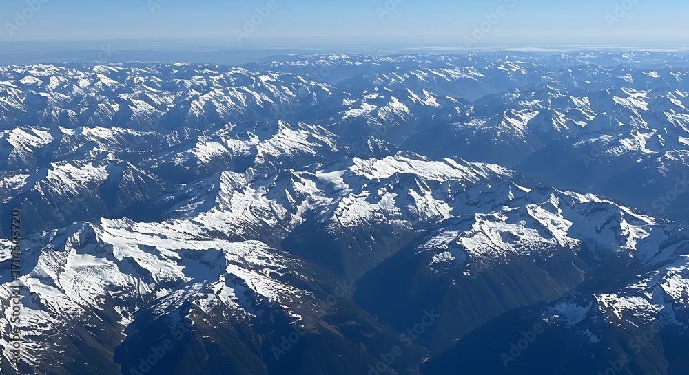 Fototapeta premium Aerial view of snow-covered mountain ranges under clear blue sky