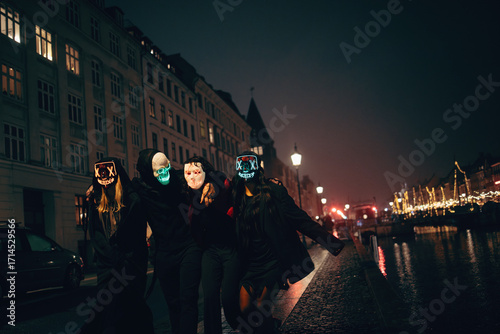 Group of friends wearing glowing masks at night in urban settings