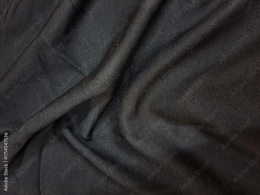 Fototapeta premium Textured black fabric with subtle geometric pattern and draping folds